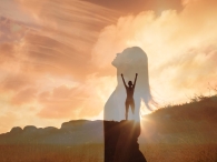 Woman,Celebrating,On,A,Mountain,Looking,Up,To,The,Sky.